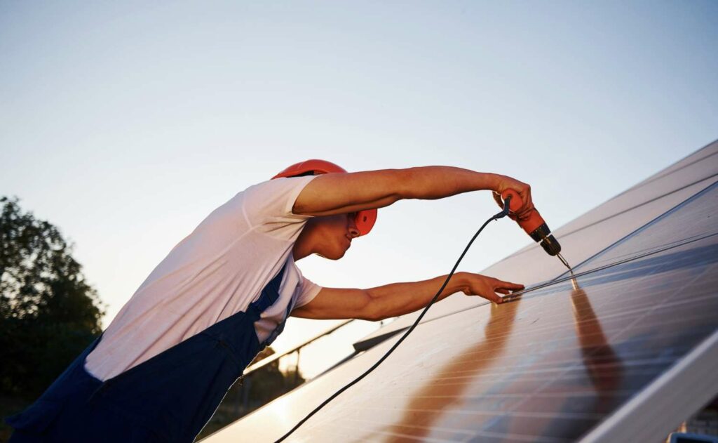 technicien installe un panneau solaire sur une maison